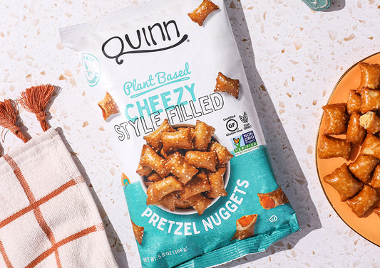 Image of a snack from Quinn Foods on a countertop with a kitchen towel and a plate of snacks on either side