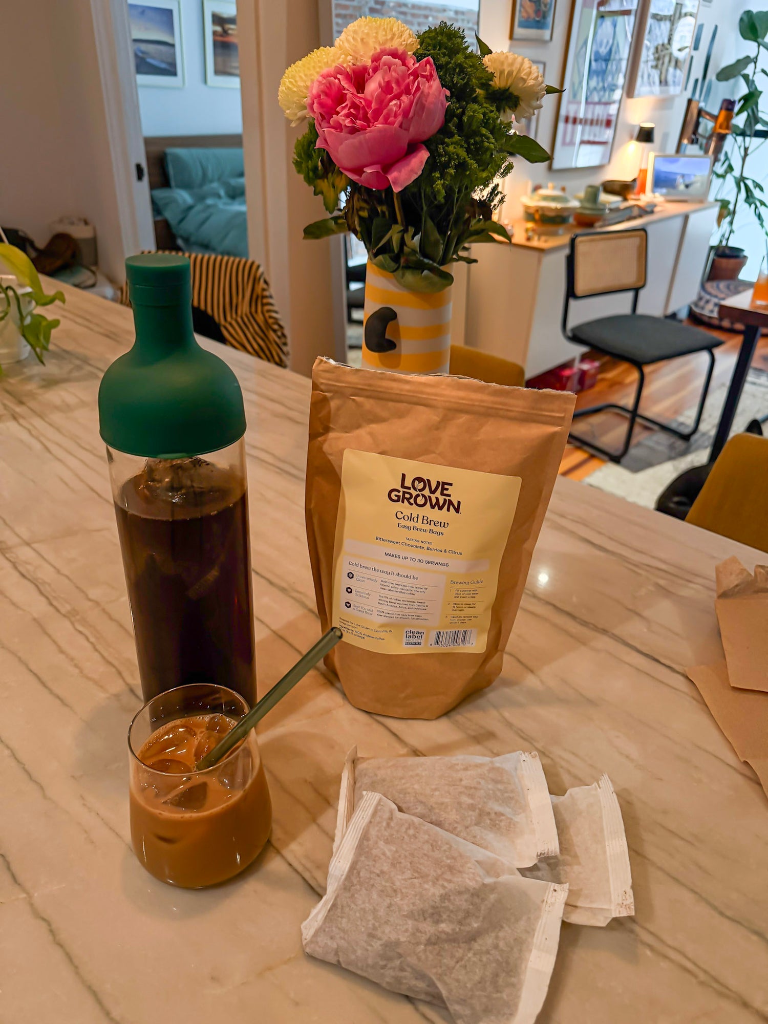 Table with a bottle, cup, and package of Love Grown cold brew coffee on a wooden surface.