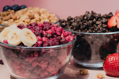 Glass bowls filled with Love Grown stars cereals topped with fruit on a pink background