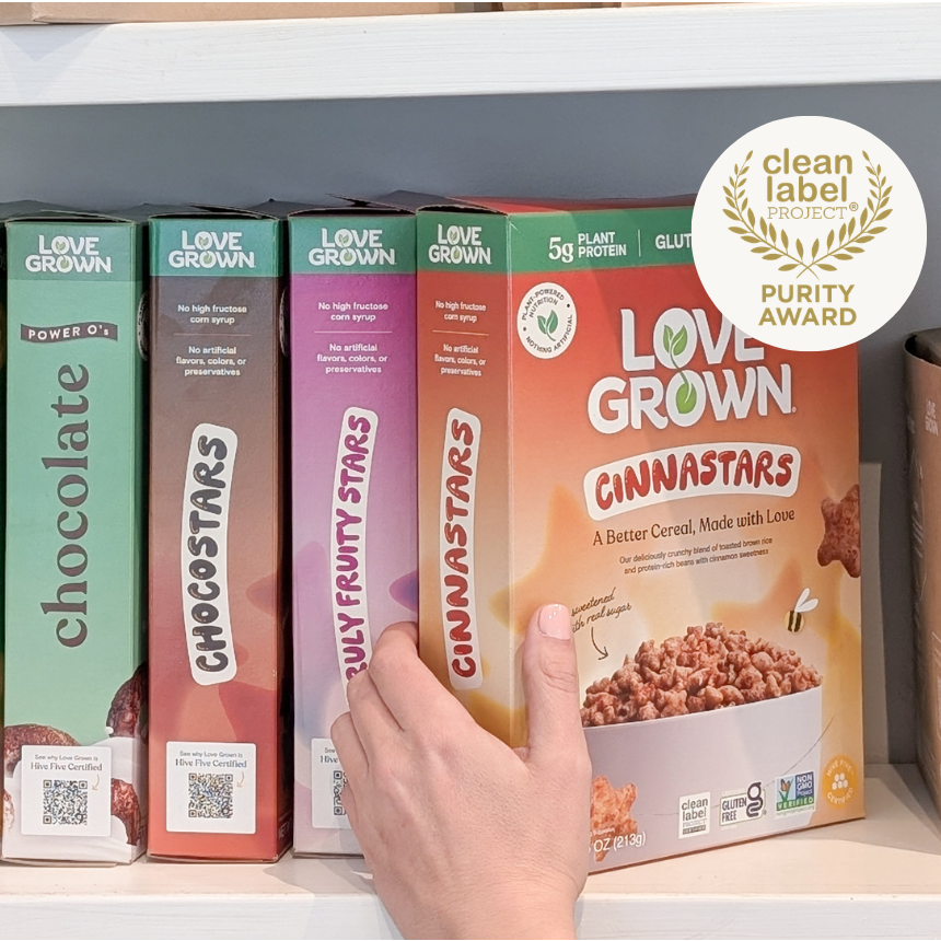 Love Grown Cinnastars cereal boxes on a shelf with a hand reaching for one, featuring the Clean Label Project purity award.