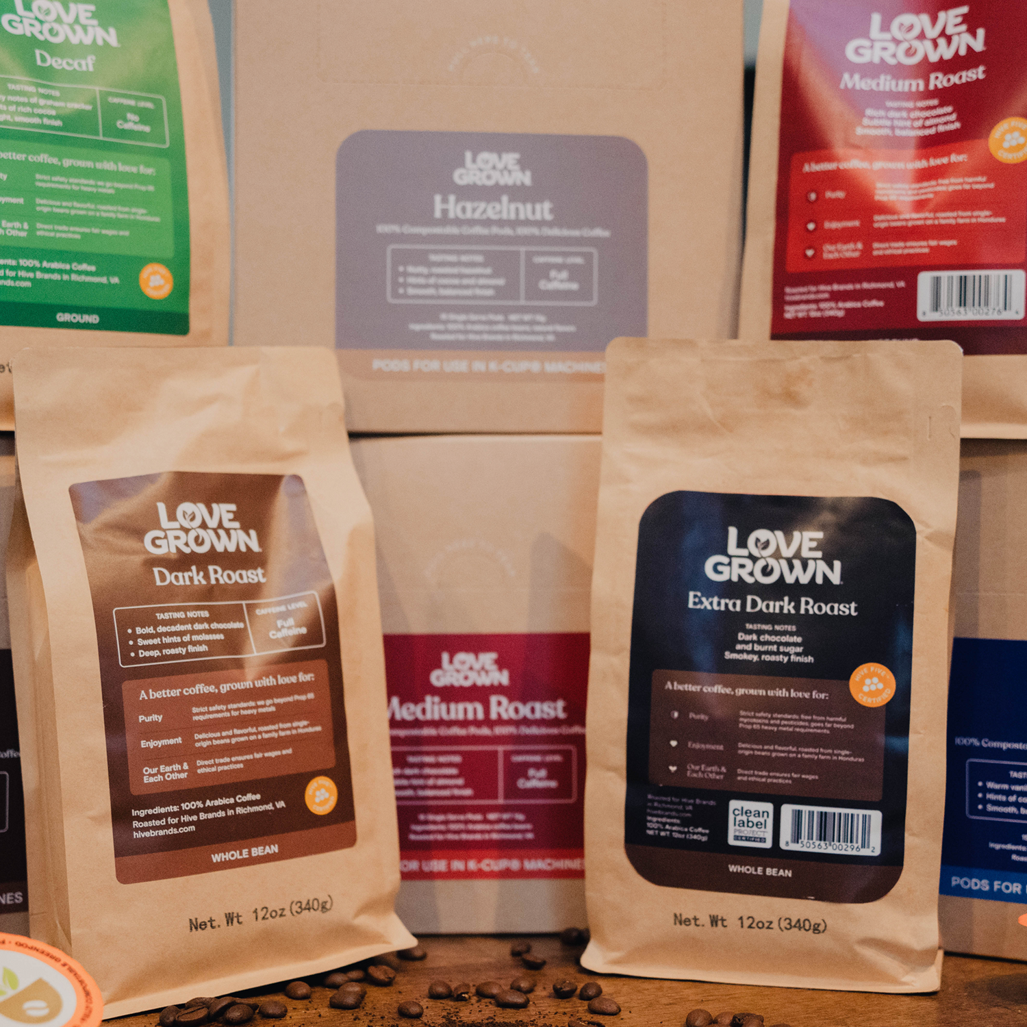 Various packages of Love Grown coffee on a wooden surface with scattered coffee beans.
